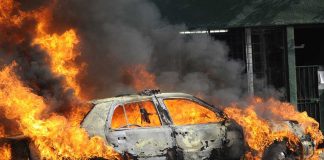 A car engulfed in flames with thick smoke billowing into the air