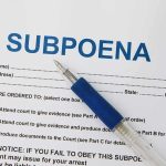 A subpoena document with a blue pen resting on it