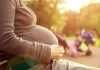 Pregnant woman sitting on a bench in a park during sunset