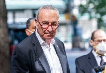 Man in suit and red glasses standing outside.