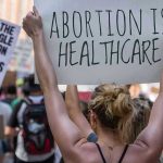 University Under Fire For Hosting Abortion Doula For Teens Protestors holding signs about womens rights and healthcare.