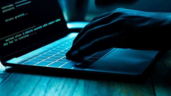 Hand typing on laptop with code on screen.