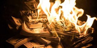 Stacks of hundred dollar bills burning in flames.