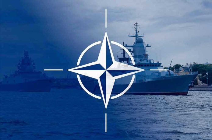 2113634360 NATO emblem overlaying naval ships in the ocean.