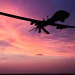 DRONE STRIKE Hits U.S.-Flagged Tanker Silhouette of a drone against a colorful sunset.