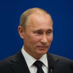 A political figure speaking at a press conference against a blue background