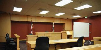 Oklahoma’s Lawsuit EXPOSES Roblox’s Safety Failures! Interior view of an empty courtroom with wooden furniture and American flags