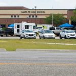 High school parking lot with emergency vehicles and tents