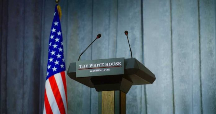 shutterstock_2448402565 Press podium with the White House sign and an American flag in the background