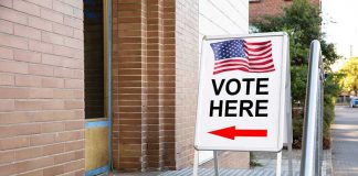 Election Gatekeepers Draw Hard Line Vote Here sign with arrow and American flag.