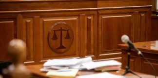 Paperwork Traps, Careers Wrecked—Then Silence Wooden courtroom desk with papers and a microphone.