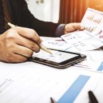 Businessperson analyzing charts with tablet and papers