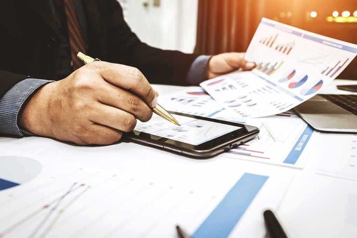 shutterstock_1008438274 Businessperson analyzing charts with tablet and papers