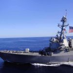 Shipping Chokehold—Who Cashes In? Naval destroyer sailing on open sea with flag flying