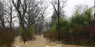 Flooded residential street with fast-moving muddy water