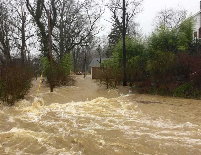 Flooded residential street with fast-moving muddy water