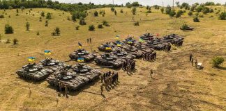 War Of Inches, Mountains Of Bodies Rows of military tanks with soldiers assembled on a dry field