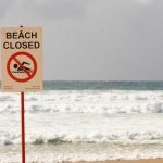 The Truth About Britain’s Beach Threats Sign indicating the beach is closed with a no swimming symbol
