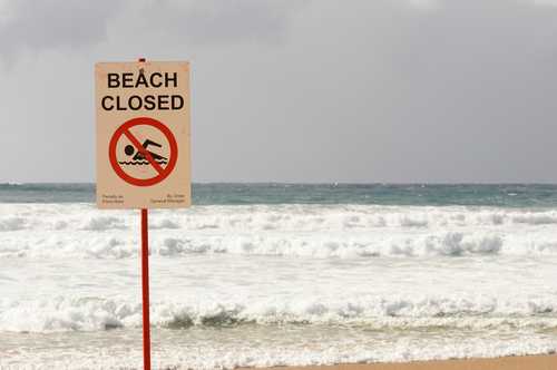 shutterstock_1985990864 Sign indicating the beach is closed with a no swimming symbol