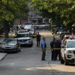 Repeat Offender, One Dead Child Police officers secure a residential street with patrol cars and yellow tape