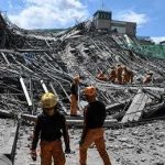 Rescue workers survey collapsed building debris