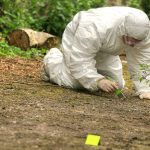 A Routine Workday Became a Hostage Crisis Forensic investigator in a protective suit collecting evidence from the ground