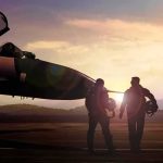 Two pilots walking beside a fighter jet at sunset