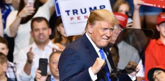 Economic D‑Day: Trump Targets Iran’s Lifelines man in suit raising fists at a rally podium