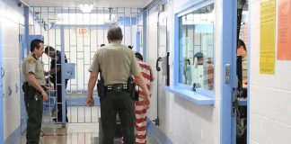 Corrections officers escort an inmate in a jail hallway