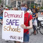School Retaliation? Mom Hits Federal Court Protester holding a sign at a city street demonstration