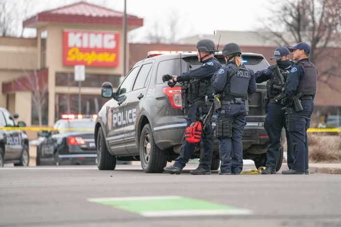 shutterstock_1941371278-1 Police officers gather beside a patrol SUV at a taped-off scene