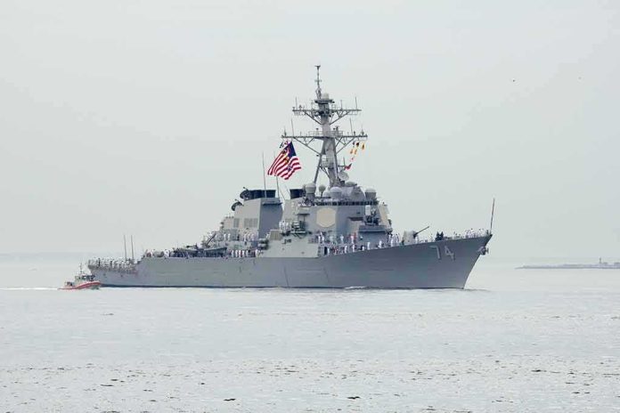 Navy destroyer with crew lined on deck at sea