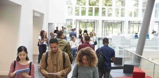 Shock Lawsuits Upend In-State Discounts Students walking through a bright campus atrium using mobile devices