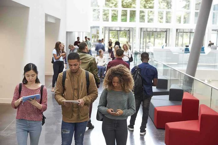 Students walking through a bright campus atrium using mobile devices