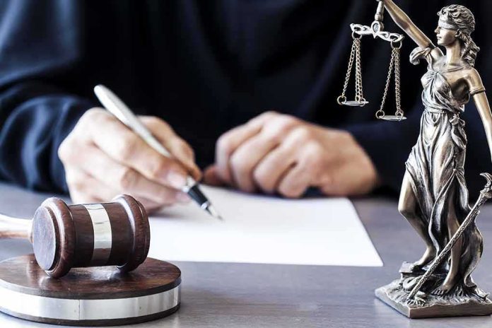 shutterstock_565403533 Judge writing at desk with gavel and Lady Justice statue