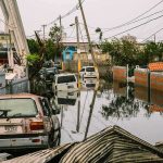 Dozens Pulled From Submerged Streets Flooded urban street with abandoned cars and downed power lines