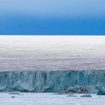 Ice cliff along a polar glacier under a blue sky