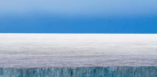 Ice cliff along a polar glacier under a blue sky