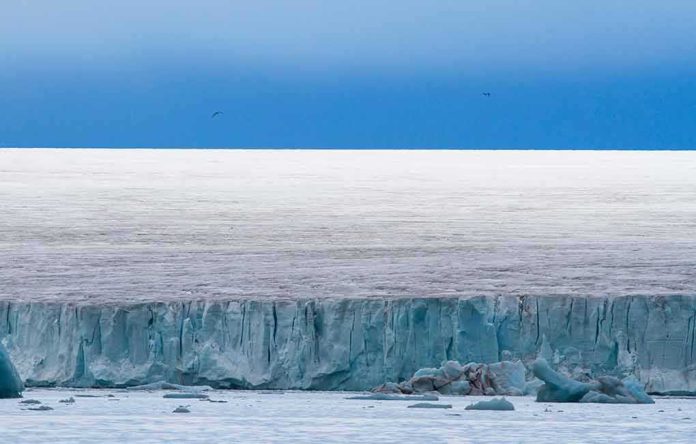 Ice cliff along a polar glacier under a blue sky
