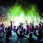 Beach Stroll Turns Venom Scare Crowd dancing in a pool under colorful lights