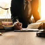 One AI Brief, One Fine, One Bar Referral Lawyer writing at desk with scales and gavel
