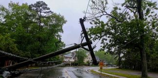 Fallen utility poles blocking a wet suburban street