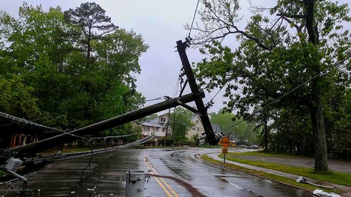 Fallen utility poles blocking a wet suburban street