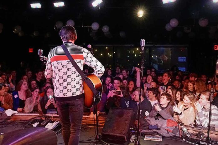 shutterstock_1160310373 Guitarist performing on stage facing a cheering crowd