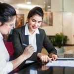 Two businesswomen reviewing documents at a desk