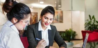 Two businesswomen reviewing documents at a desk