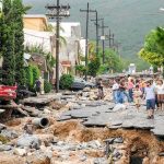 Rescuers Blocked, Families Wait Residents walk along a heavily damaged street after a disaster