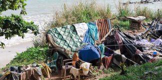 makeshift shelter near a beach with tarps and clothes drying