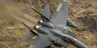 Fighter jet banking low over rugged terrain