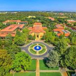 Aerial view of a university campus with central fountain and red-tiled buildings